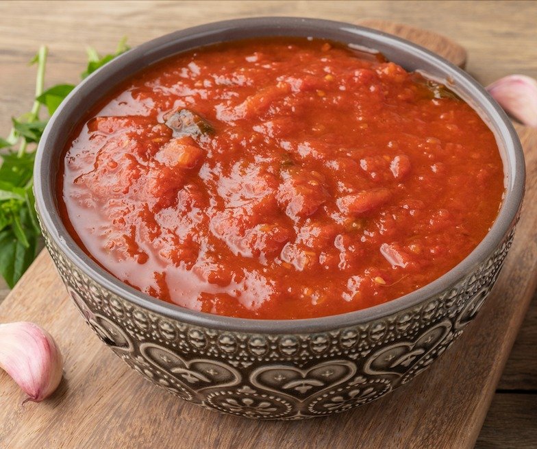 A bowl of Mariana sauce on a cutting board for Mediterranean diet recipes